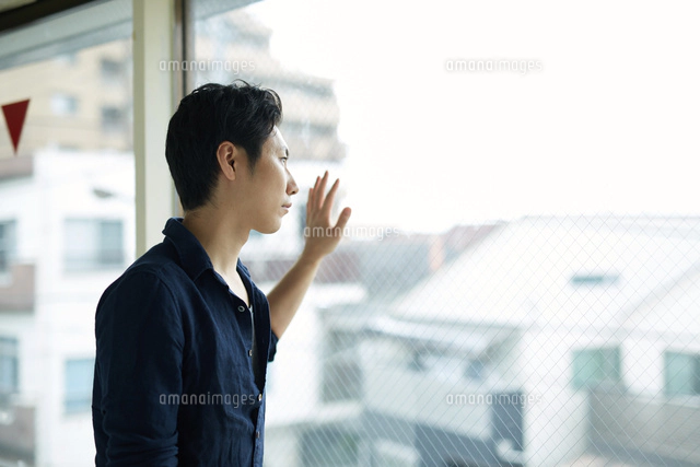 将来の結婚や婚活に不安を感じながら外を見つめる日本人男性